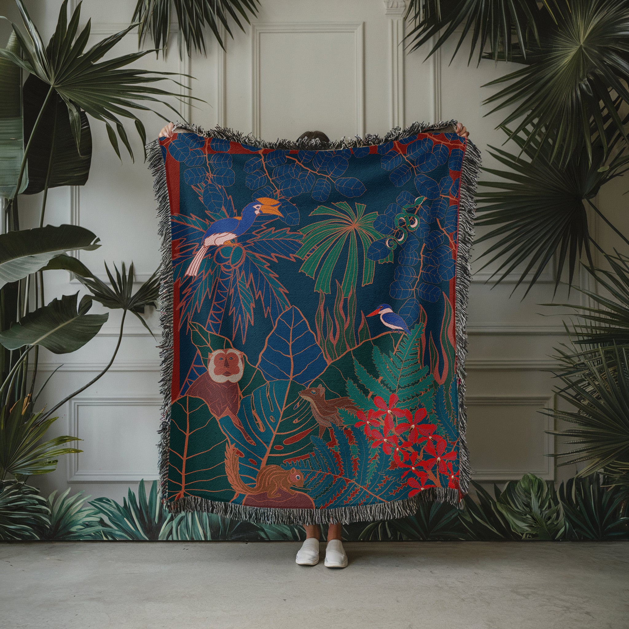 Colorful tapestry with jungle design held by a person against a white paneled wall with green plants.
